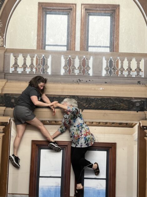 Two women giving the illusion of falling off a balcony at the Museum of Illusions St. Louis