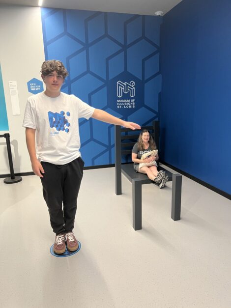 A large teen pointing to his shrunken mom in the Museum of Illusions St. Louis.