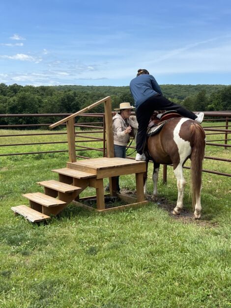 Tanya helps new rider get on horse.