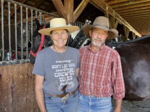 Tanya and Roy Schoenbeck wearing cowboy gear in their barn at RS Ranch.