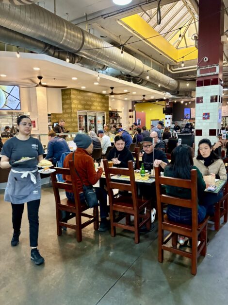 Server brings food to a table at Mercado La Paloma